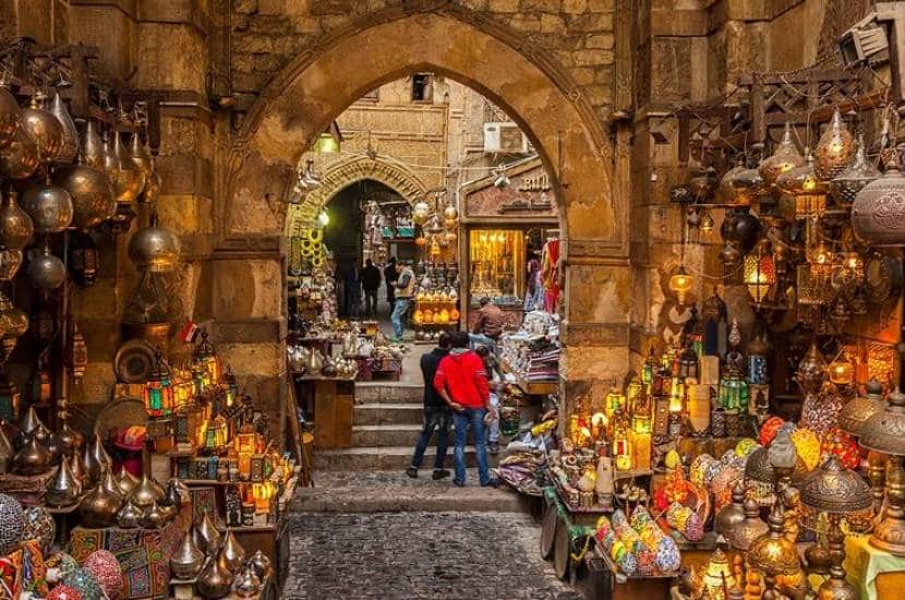Traditional shopping street on Al Muizz Street in Islamic Cairo with historic buildings and local shops

